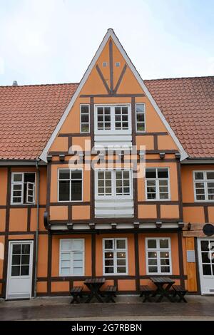 Historisches und typisch orange und hölzern bemaltes Fachwerkgebäude mit weißen Fenstern und Türen im Stadtzentrum von Aalborg, Dänemark. Stockfoto