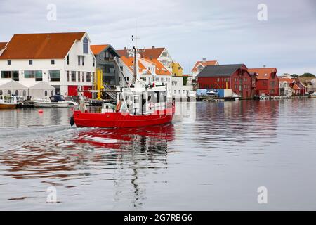 Typisches Fischerboot mit traditionellen Holzgebäuden entlang der Uferpromenade, des Flusses und des Yachthafens. Smedasundet, Stadtzentrum, Haugesund, Norwegen. Stockfoto