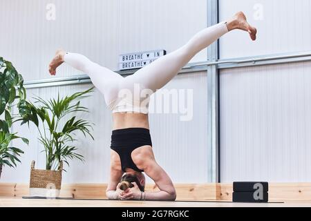 Junge schöne Yoga weiblich posiert invert im Studio Stockfoto