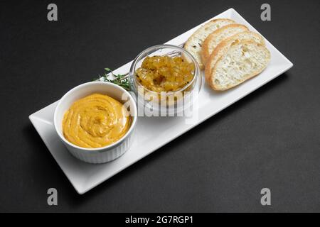 Nahaufnahme von Gänseleber-Pastete mit Apfelchutneys und Brot auf schwarzem Hintergrund Stockfoto