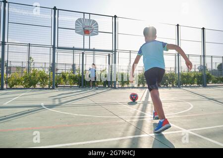 Zwei Brüder spielen Fußball, einer von ihnen hat eine Beinprothese und der andere tritt eine Strafe. Geschwister spielen zusammen Sport. Stockfoto