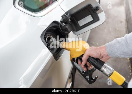 Gelbe Zapfpistole von Hand halten und Fahrzeug nachfüllen Stockfoto