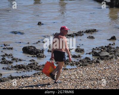 Sheerness, Kent, Großbritannien. Juli 2021. Wetter in Großbritannien: Ein Mann geht an einem sonnigen und warmen Morgen am Strand entlang in Sheerness, Kent. Kredit: James Bell/Alamy Live Nachrichten Stockfoto