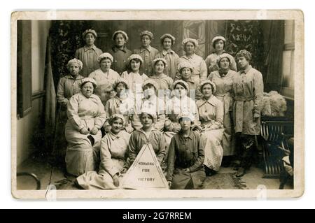 Der originale Postkartenhinweis aus der WW1. Epoche lautet „Working for Victory“. Um den Rand herum sind die Royal Arsenal Danger Buildings Woolwich Arsenal gedruckt. Eine Gruppe weiblicher Munitionetten, die um 1916, 1917 herum auf Kriegsdienstmarken getragen wurden, war Arsenal eine Fabrik für Muschelfüllungen. Woolwich, London, Großbritannien Stockfoto