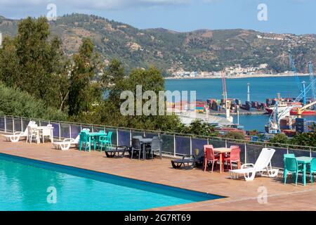 Plastikstühle mit Tischen und Sonnenliegen in der Nähe des Pools. Stockfoto