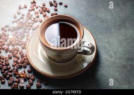 Duftender starker Kaffee und Kaffeebohnen auf dunkelgrünem Betongrund. Das Konzept der Heißgetränke. Kopieren Sie Platz für Ihren Text Stockfoto