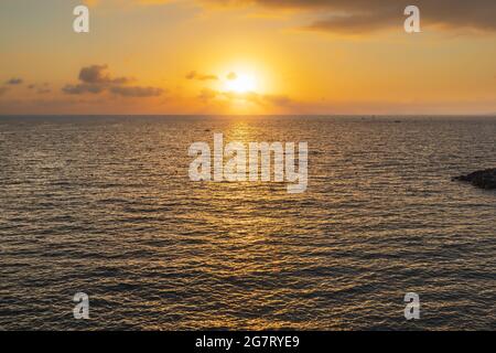 Schöner Sonnenuntergang über dem Meer mit Sonne hinter Wolken Stockfoto