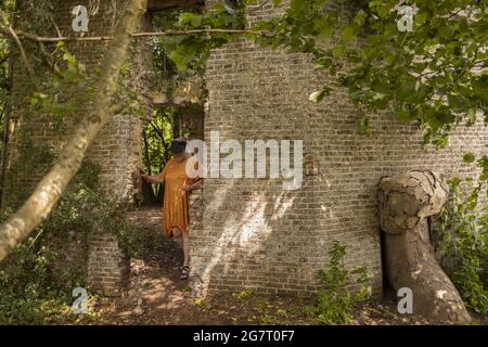 ZUTPHEN, NIEDERLANDE - 04. Jul 2021: Frau, die in Steinruinen einer alten, von Vegetation bewachsenen Windmühle herumläuft Stockfoto