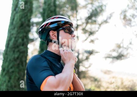 Kaukasischer männlicher Biker, der seinen Fahrradhelm in der Natur befestigt Stockfoto