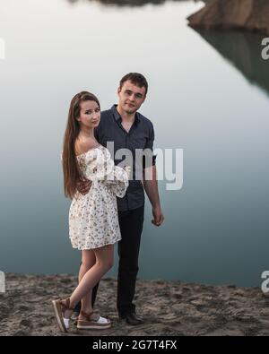 Junger Mann und Mädchen gehen neben dem See. Verliebte Paare verbringen die Zeit für immer zusammen Stockfoto
