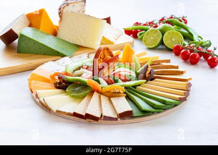 Käseplatte auf weißem Holzhintergrund. Käseplatte. Käsesorten. Käseplatte auf dem Tisch. Antipasto Set Platte. Vertikale Ansicht Stockfoto