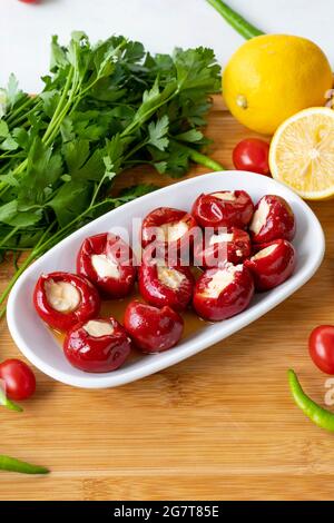 Mit Käse gefüllte Kirschpaprika auf Holzhintergrund Stockfoto