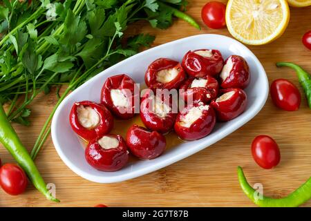 Mit Käse gefüllte Kirschpaprika auf Holzhintergrund Stockfoto