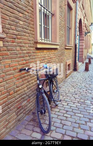 Blick auf eine Seitenstraße in der historischen Altstadt von Düsseldorf, Deutschland, mit Vintage-Fahrrad, Backsteingebäude und Pflastersteinpflaster. Stockfoto