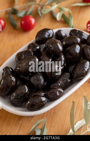 Schwarze Kalamata-Oliven. Leckere kalamata-Oliven auf dem Teller. Kalamata Oliven auf Holzhintergrund Stockfoto