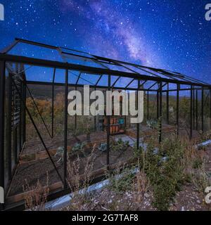 Quadratischer Rahmen Glasgewächshaus auf der Rückseite eines Hauses unter einem atemberaubenden Composite Milchstraße Himmel Stockfoto