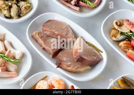 Auswahl an Fischgerichten. Meeresfrüchte auf einem Teller. Auf einem weißen Holzhintergrund. Selektiver Fokus Shrimp. Garnelen, Lakerda, Oktopus-Salat, Muscheln mit Marinade Stockfoto