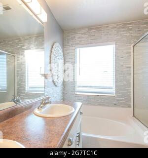 Quadratisches Master-Badezimmer mit einem warmen Blitz und Steinfliesen an den Wänden Stockfoto