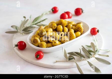 Gegrillte grüne Oliven. Leckere grüne Bio-Oliven auf dem Teller. Olive auf Marmorboden Stockfoto