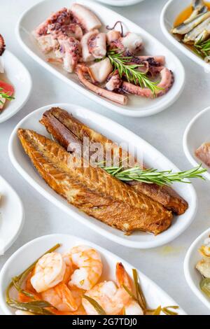 Auswahl an Fischgerichten. Meeresfrüchte auf einem Teller. Auf einem weißen Holzhintergrund. Selektiver Fokus marinierte Sardellen. Lakerda, Kraken-Salat, Garnelen, Fischsalat Stockfoto