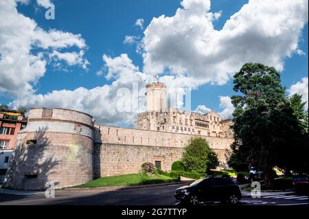 Trient, Italien, Juni 2021. Das imposante Schloss von Buonconsiglio, ein dreiviertel Blick von der Straße, die entlang der Mauern verläuft. Schöner Sommertag. Stockfoto