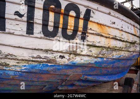Blick auf eine alte abgenutzte Bootsseite im Trockendock mit Farbabblättern von der Seite. Stockfoto