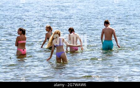 Dundee, Tayside, Schottland, Großbritannien. Juli 2021. UK Wetter: Heisses, sonniges Wetter, das durch Nordostschottland weht mit einer Höchsttemperatur von 29 Grad Strandbesucher können den Tag am Broughty Ferry Beach in Dundee ausklingen lassen und die warme, herrliche Sommersonne genießen. Fünf junge Menschen spielen im Wasser, bevor sie im Fluss Tay schwimmen gehen. Kredit: Dundee Photographics/Alamy Live Nachrichten Stockfoto