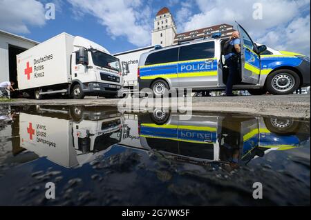 Dresden, Deutschland. Juli 2021. Lastwagen des DRK (Deutsches Rotes Kreuz) und ein Polizeiauto sind auf dem Gelände des DRK abfahrbereit und spiegeln sich in einer Pfütze. Sachsen schickt Ausrüstung für Notunterkünfte in die Katastrophenregion Rheinland-Pfalz und bittet um Spenden für die von den verheerenden Überschwemmungen dort und in Nordrhein-Westfalen Betroffenen. Quelle: Robert Michael/dpa-Zentralbild/dpa/Alamy Live News Stockfoto