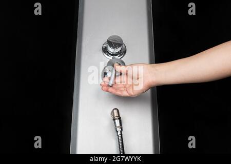 Die Frau schaltet den Mixer in der Dusche mit kaltem und heißem Wasser aus der Nähe und schaltet Leitungswasser für die Körperhygiene ein. Stockfoto