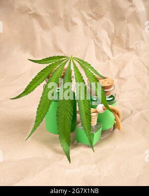 Flaschen mit Extraktöl und medizinischem Cannabis auf Papierhintergrund. Stockfoto