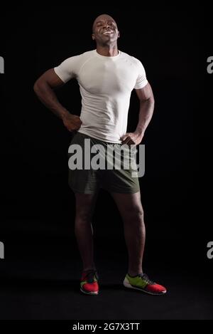 Afroamerikanischer Mann, der mit den Fäusten auf der Hüfte auf die Kamera schaut Stockfoto