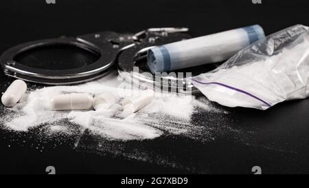 Drogenstrafen, Handschellen und weißes Kokainpulver Stockfoto