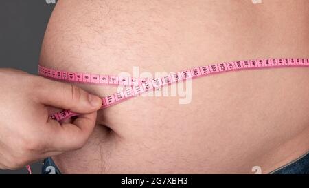 Adipositas-Konzept, messen Sie einen großen dicken Bauch mit einem Zentimeter. Stockfoto