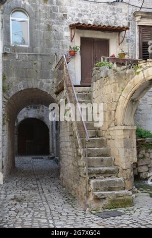 Vertikale Aufnahme einer schönen alten Treppe, die zu einem Backsteingebäude mit einem Tunnel an der Seite führt Stockfoto
