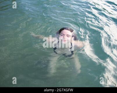 Lächelnde junge Frau in schwarzem Bikini aus dem Wasser Stockfoto