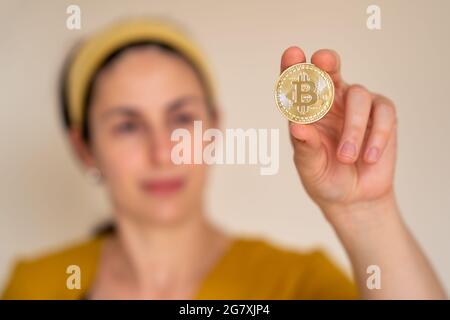 Nahaufnahme einer Frau, die Bitcoin-Kryptowährungsmünze in der Hand hält Stockfoto