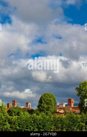 Lucca charmante Skyline des historischen Zentrums mit wunderschönen Wolken und mittelalterlichen Türmen erhebt sich über den umliegenden Anciet Walls Park Bäume Stockfoto