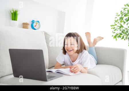 Foto-Porträt kleines Mädchen auf der Couch zu sehen Online-Lektion lachen halten Stift Stockfoto