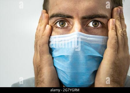 Porträt eines jungen blonden Mannes aus Argentinien in einer chirurgischen Gesichtsmaske in Schock Stockfoto