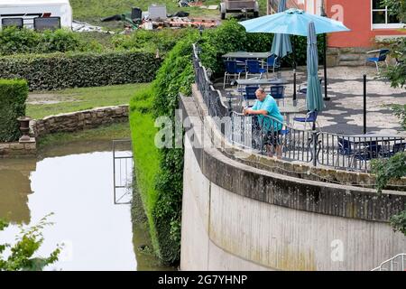 Hattingen, NRW, Deutschland. Juli 2021. Ein Mann sieht sich die Schäden an den Gärten und dem Grundstück im Hotel 'an der Kost' an. Die Ruhr hat ihre Böschung, Felder und viele Gärten, Keller und Grundstücke in der Nähe der Stadt Hattingen im Ruhrgebiet in Nordrhein-Westfalen überflutet. NRW ist nach starken Regenfällen in den letzten Tagen von schrecklichen Überschwemmungen heimgesucht worden. Bei den Überschwemmungen in Deutschland sind bisher mehr als 80 Menschen ums Leben gekommen. Kredit: Imageplotter/Alamy Live Nachrichten Stockfoto