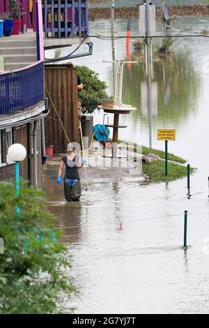 Hattingen, NRW, Deutschland. Juli 2021. Eine Frau in Fischerwadern außerhalb eines Grundstücks. Die Ruhr hat ihre Böschung, Felder und viele Gärten, Keller und Grundstücke in der Nähe der Stadt Hattingen im Ruhrgebiet in Nordrhein-Westfalen überflutet. NRW ist nach starken Regenfällen in den letzten Tagen von schrecklichen Überschwemmungen heimgesucht worden. Bei den Überschwemmungen in Deutschland sind bisher mehr als 80 Menschen ums Leben gekommen. Kredit: Imageplotter/Alamy Live Nachrichten Stockfoto