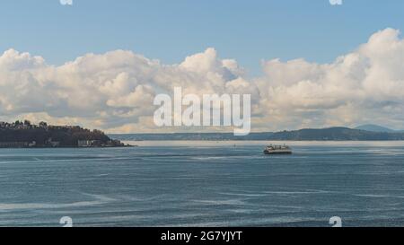 Die Washington Ferry fährt auf der Elliot Bay vorbei an West Seattle und Wolkenhimmel im Hintergrund Stockfoto