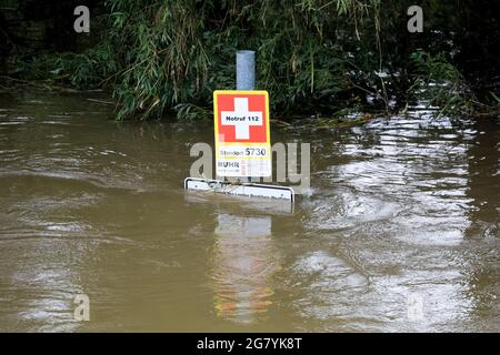 Hattingen, NRW, Deutschland. Juli 2021. Ein „SOS“-Schild mit Standort- und Notfallkontaktinformationen, das normalerweise an Wanderer gerichtet ist, ist fast unter Wasser, wobei der Wasserstand an dieser Stelle mindestens 1.5 Meter höher ist. Die Ruhr hat ihre Böschung, Felder und viele Gärten, Keller und Grundstücke in der Nähe der Stadt Hattingen im Ruhrgebiet in Nordrhein-Westfalen überflutet. NRW ist nach starken Regenfällen in den letzten Tagen von schrecklichen Überschwemmungen heimgesucht worden. Bei den Überschwemmungen in Deutschland sind bisher mehr als 80 Menschen ums Leben gekommen. Kredit: Imageplotter/Alamy Live Nachrichten Stockfoto