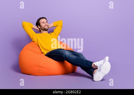 In voller Länge Körpergröße Foto Mann liegt in Sitzsack chillig verträumt suchen Kopyspace isoliert pastelllila Farbe Hintergrund Stockfoto