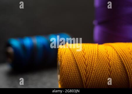 Nahaufnahme von verschiedenen bunten Fadenrollen auf einem schwarzen Holztisch Stockfoto