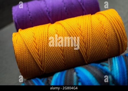 Nahaufnahme von verschiedenen bunten Fadenrollen auf einem schwarzen Holztisch Stockfoto
