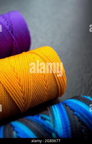 Nahaufnahme von verschiedenen bunten Fadenrollen auf einem schwarzen Holztisch Stockfoto
