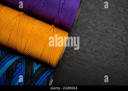 Nahaufnahme von verschiedenen bunten Fadenrollen auf einem schwarzen Holztisch Stockfoto