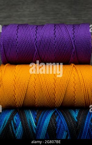 Nahaufnahme von verschiedenen bunten Fadenrollen auf einem schwarzen Holztisch Stockfoto