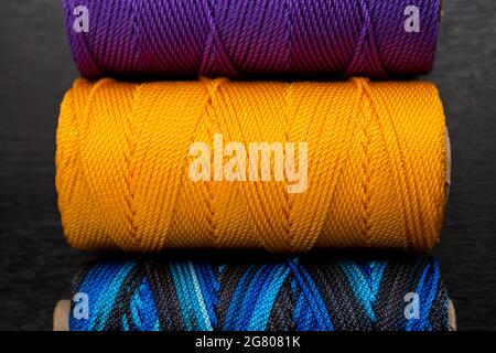 Nahaufnahme von verschiedenen bunten Fadenrollen auf einem schwarzen Holztisch Stockfoto